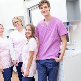 Ein freundliches Zahnarztpraxis-Team steht gemeinsam in moderner Behandlungsumgebung.