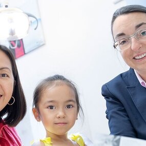 Eine Frau mit Kind sitzt im Beratungsraum bei einer freundlichen Zahnärztin.